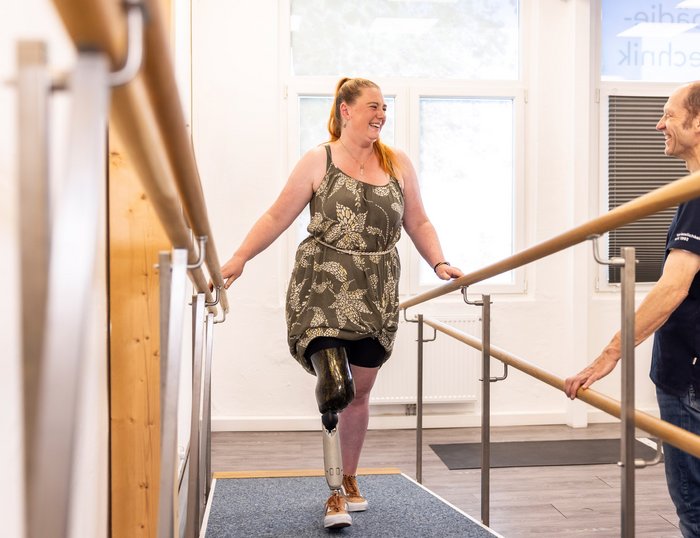 Gangtraining mit Prothese im MOT-Sanitätshaus Frau mit Beinprothese übt das Gehen auf einer Gehbühne unter Anleitung eines MOT-Mitarbeiters