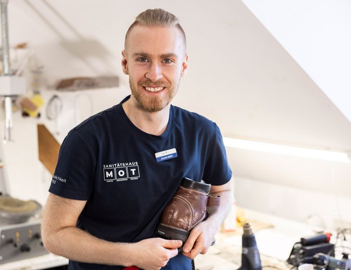 Orthopädieschuhtechniker in MOT-Werkstatt Motivierter Orthopädieschuhtechniker in der MOT-Werkstatt am Bearbeiten eines Schuhs